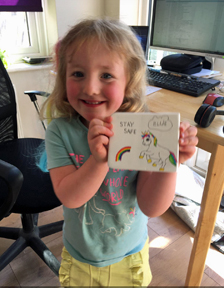 a girl holding square tile painted with a unicorn and a rainbow